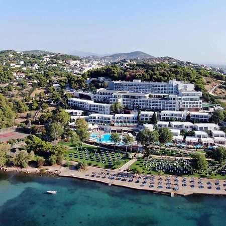 Dolce By Wyndham Athens Attica Riviera Hotel Vravrona Exterior photo The image shows a large hotel complex situated near a beach. It's located on a hillside, surrounded by greenery and trees. The hotel features multiple levels with modern architecture, balconies, and a swimming pool area. In front of the hotel, there'