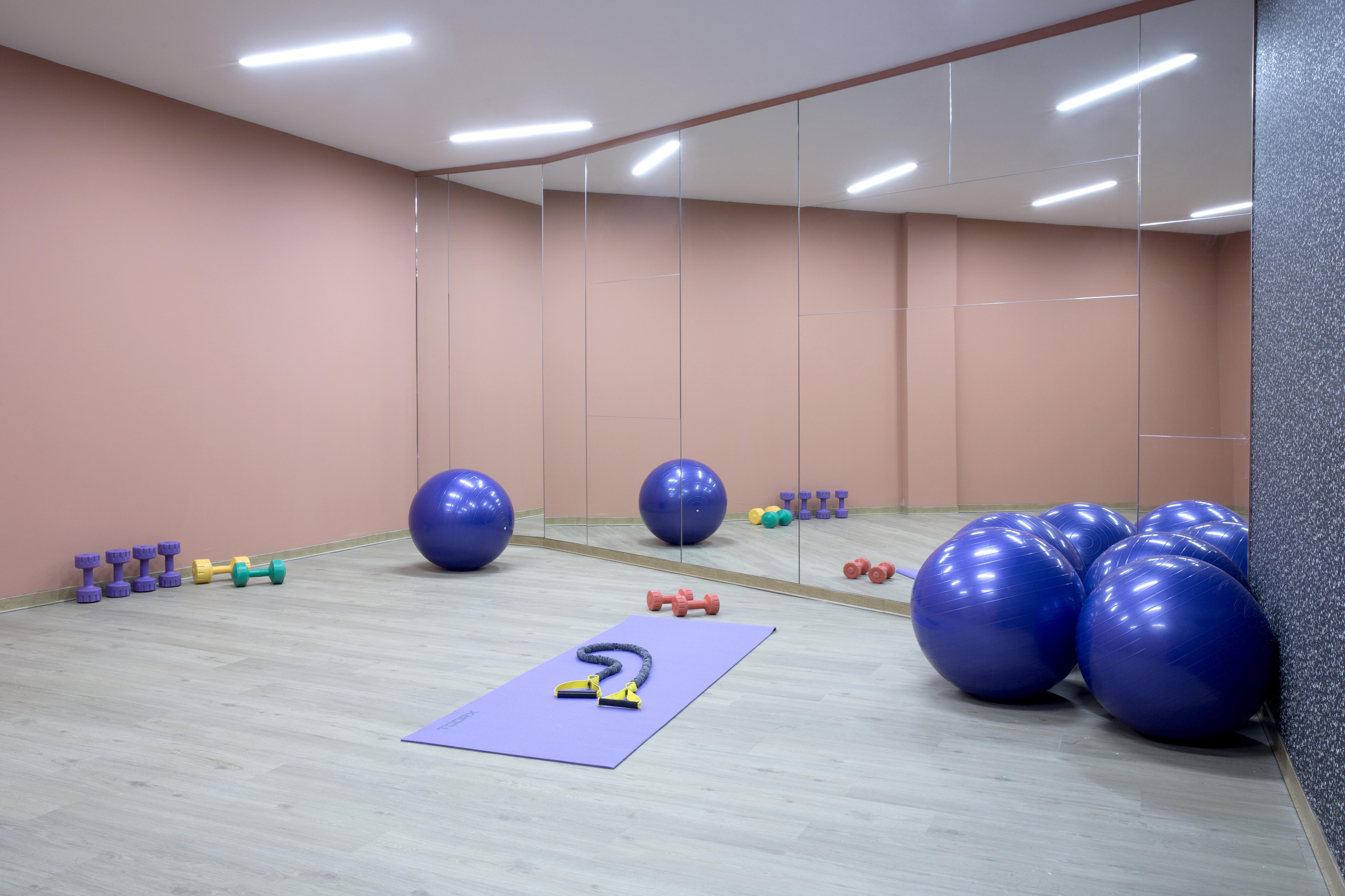 Dolce By Wyndham Athens Attica Riviera Hotel Vravrona Exterior photo The photo shows a fitness or exercise room. The walls are painted a soft pink color, and there are large mirrors on one side. Various workout equipment is visible: there are purple exercise balls stacked in one corner, a yoga mat laid out on the floo